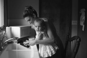 Mother and child washing hands in kitchen sink