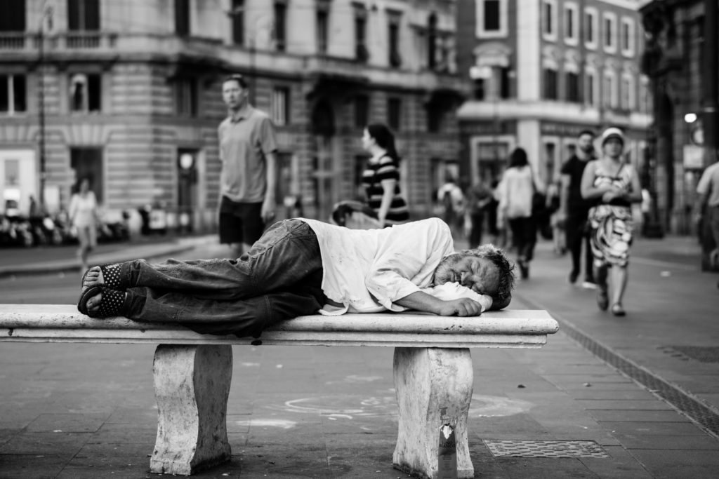 Man asleep on stone bench in a pedestrian precinct