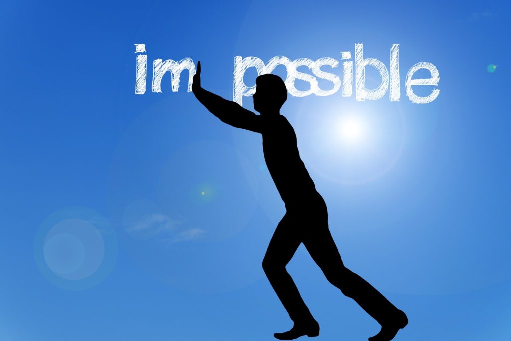 Man pushing the letters im away from the word impossible, leaving the word possible
