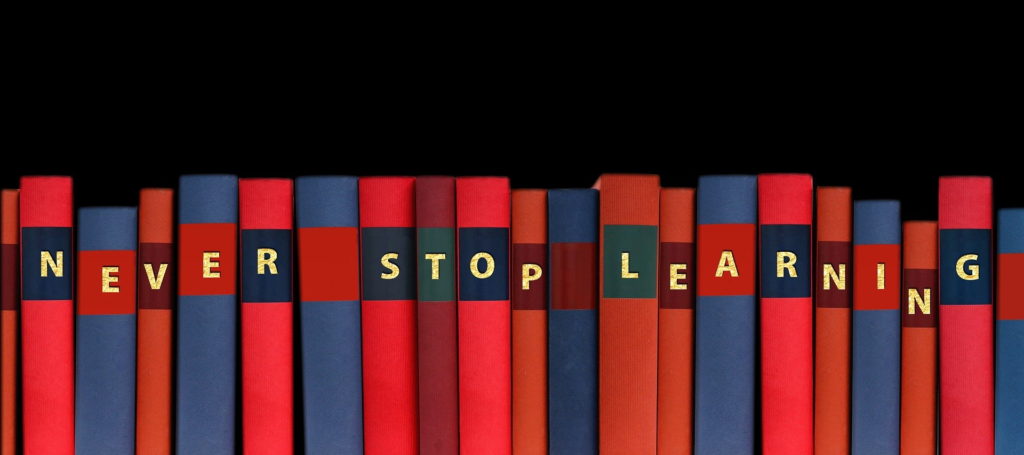 shelf of books with letters on spines spelling the words Never Stop Learning