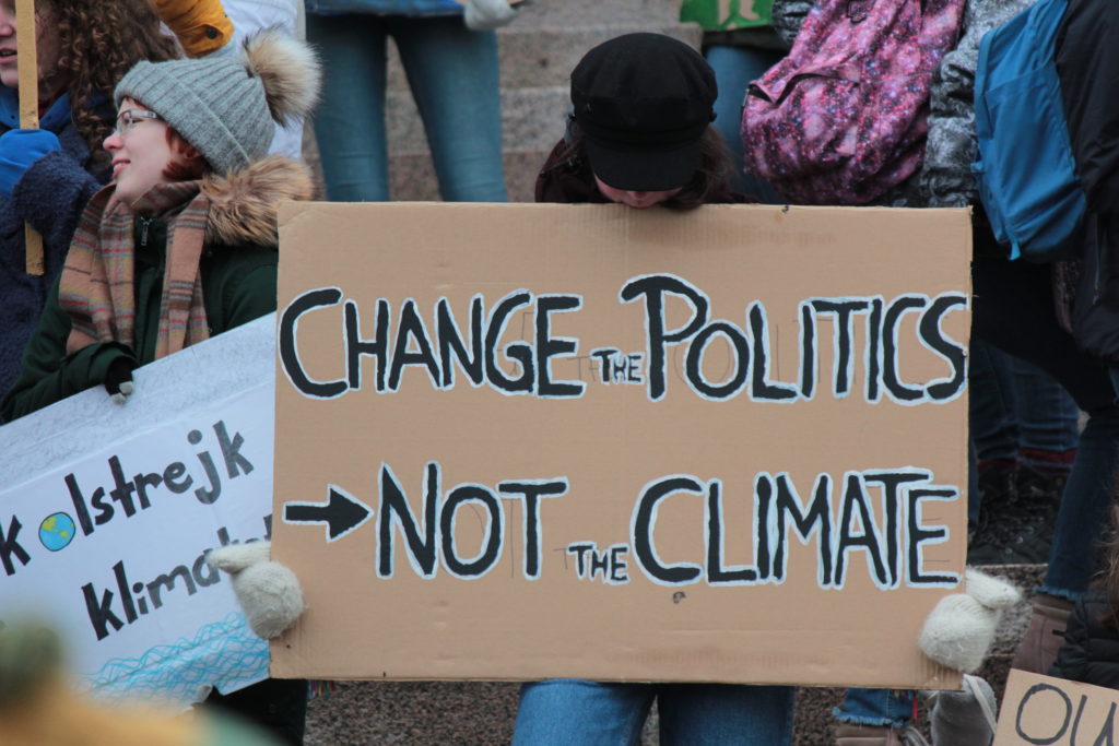 Protester holding sign with slogan "Change the politics not the climate"