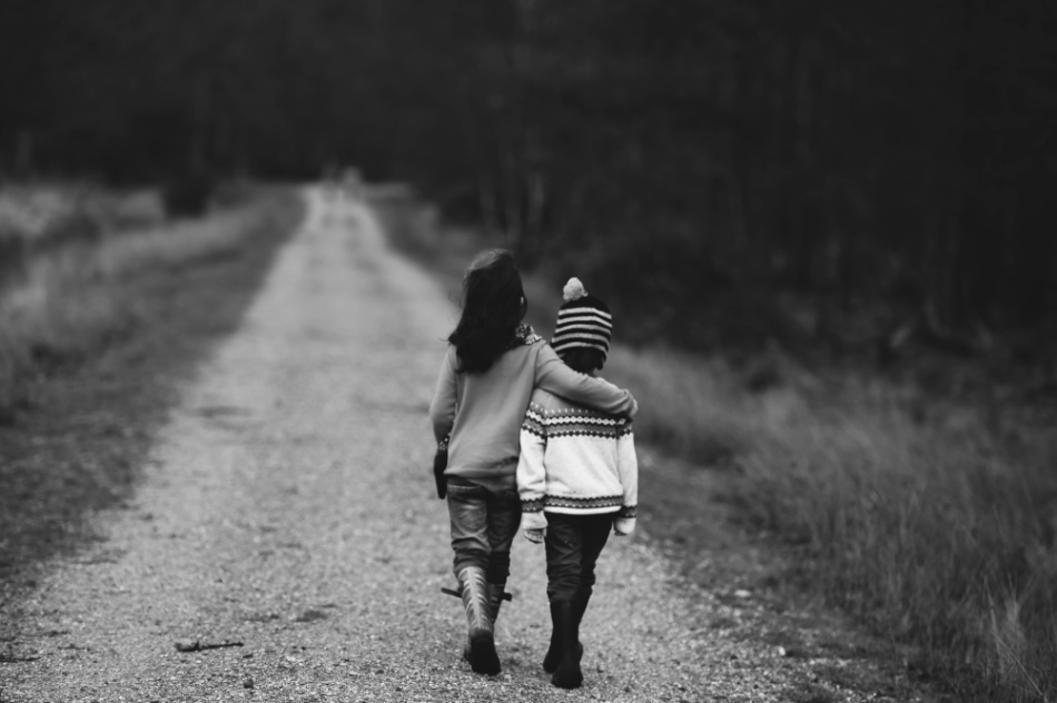Two children walking away on a path with their arms around each other
