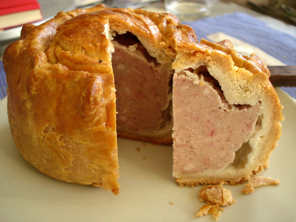 A pork pie with a slice cut out of it