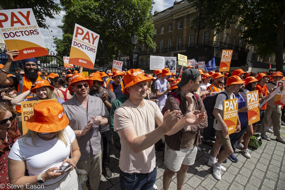 Junior Doctors wearing orange BMA bucket hats and holding placards on a picket line