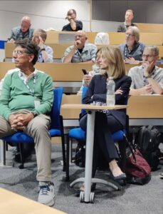 Warren Mosler and Stephanie Kelton listen to a presentation
